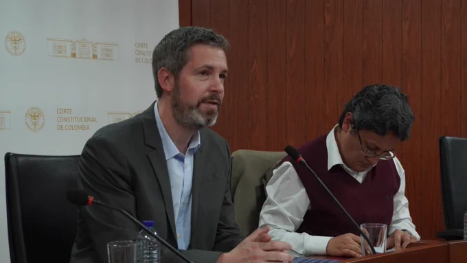 Professor David Pozen and Professor Vicente Benítez seated before microphones at the Constitutional Court of Colombia. Pozen is speaking.