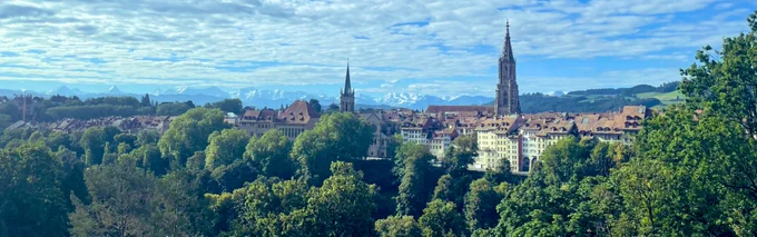 Panoramic view onto the old town of Bern, with mountains in the background.