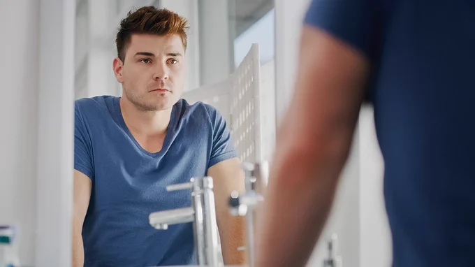 Person looking at themself in their bathroom mirror