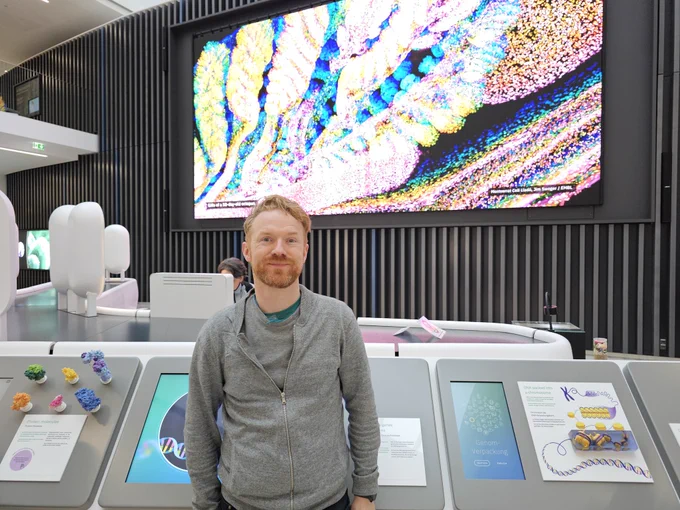 Phil stood in front of colourful large display and interactive museum displays