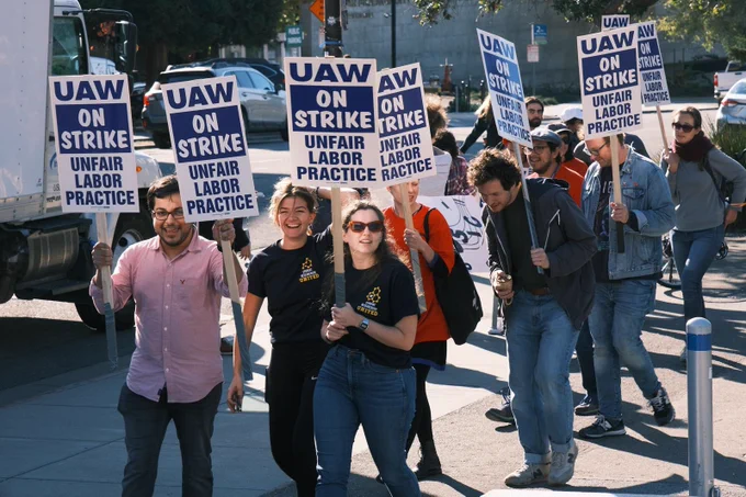 Group of people walking with UAW strike picket signs
