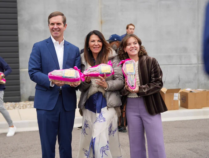 An image of Governor Beshear and two women holding Stellar Snacks pretzels.