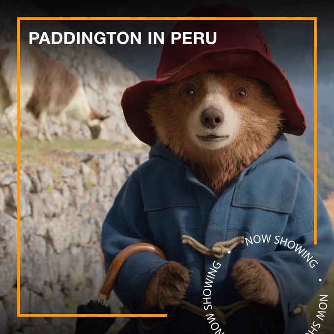 Paddington, a small brown bear wearing a blue duffle coat and a red hat, stands in a field with goats behind him. Text - Paddington in Peru, Now Showing