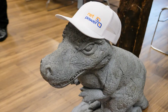 A small dinosaur statue with a white net power cap on

