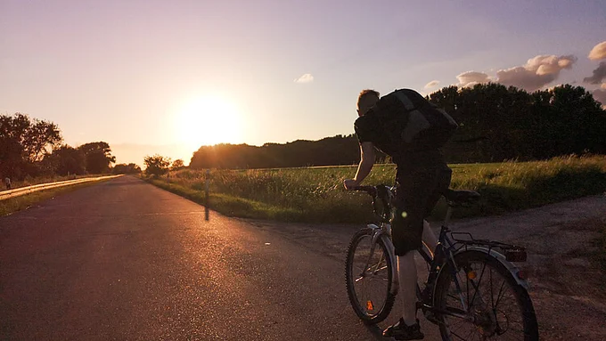 Fotograph of Jan-Felix Müller, riding a bike into the sunset