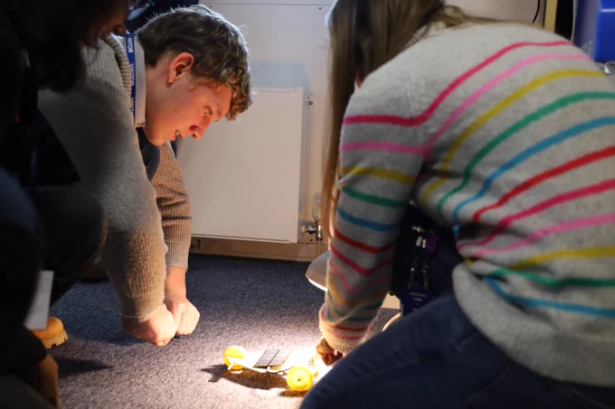 Student looking at model car glowing on the floor