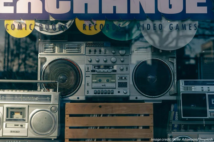 Portable “boombox” stereos sitting behind a display window in a music shop. Image credit: Nellie Adamyan/Unsplash