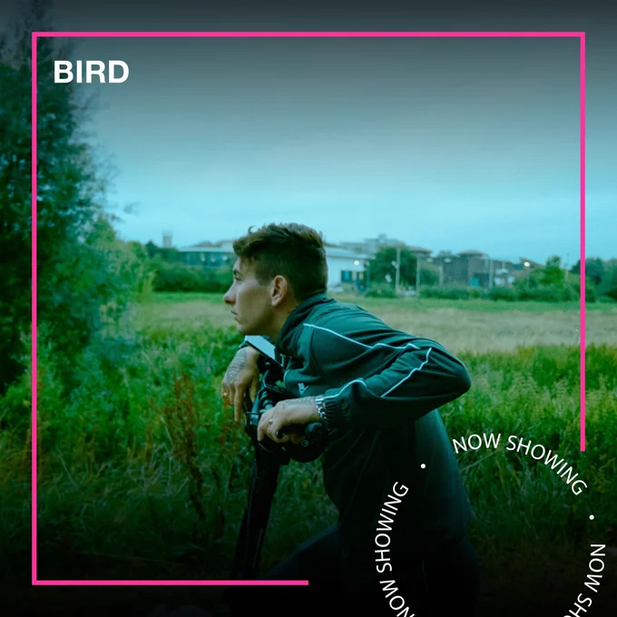 Barry Keoghan leans on a bike in a field. Text - Bird, Now Showing