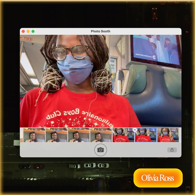 Olivia's photo in photobooth, she has dark skin, hair in two buns, glasses and is wearing a mask, seems to be on a train. She is winking at the camera. 