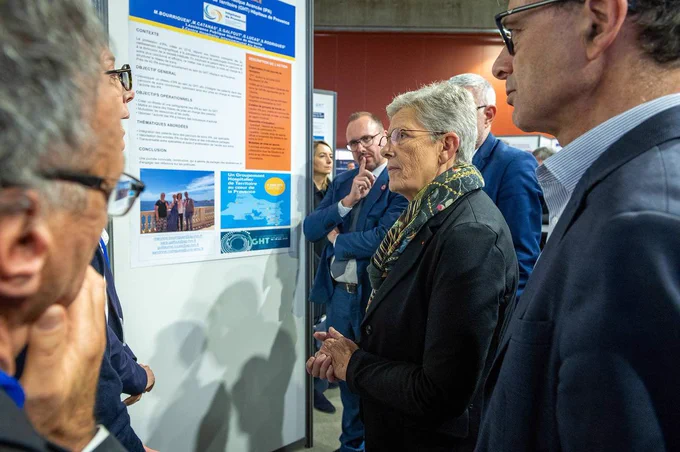 Geneviève Darrieussecq est entourée de plusieurs personnes, à côté d’un panneau d’exposition sur les GHT.