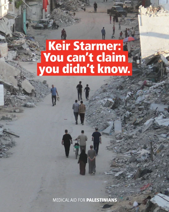 A photograph of a destroyed urban area in North Gaza with people walking down a road. The centre of the road has been neatly cleared. Banks of rubble  line the road. The text reads: 'Keir Starmer: You can’t claim you didn’t know.'