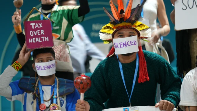 activists hold signs demanding climate action during a silent protest at COP29