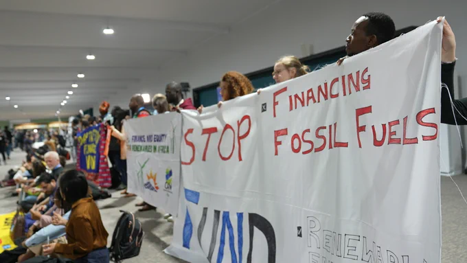activists hold signs demanding climate action during a silent protest at COP29