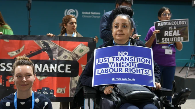 activists hold signs demanding climate action during a silent protest at COP29