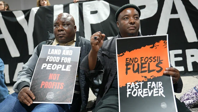 activists hold signs demanding climate action during a silent protest at COP29