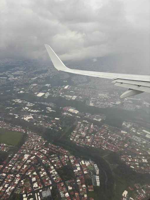 A view of Costa Rica from a plane window, with the plane wing in the top right of the photo