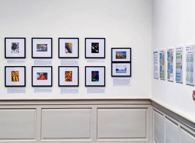 A white gallery wall displaying ten photo frames and caption plaques.