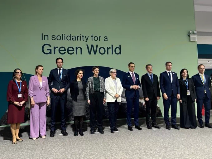 Canada’s Ambassador for Climate Change, Catherine Stewart, standing with delegates in front of backdrop written “In Solidarity for a Green World”