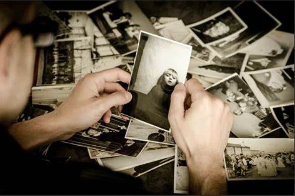 A man looking at various black-and-white photographs of people.