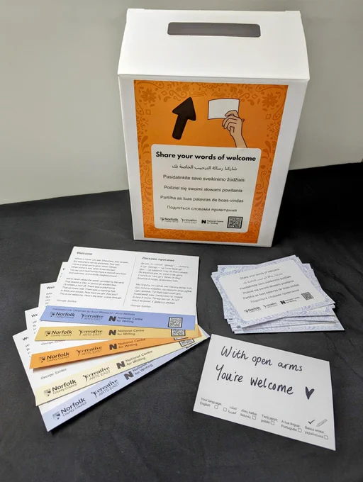 A cardboard post box with a set of postcard in front of it