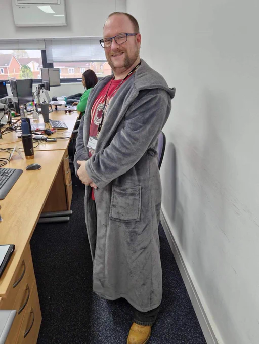 Man stood smiling in a grey dressing gown in Vizion Network's office space in The Deep Business Centre. 