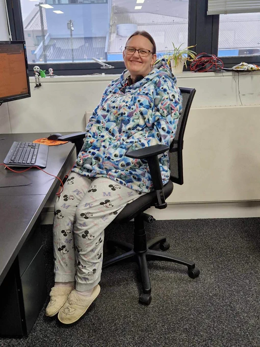 Woman sat smiling in a stitch-themed oodie in Vizion Network's office space in The Deep Business Centre. 