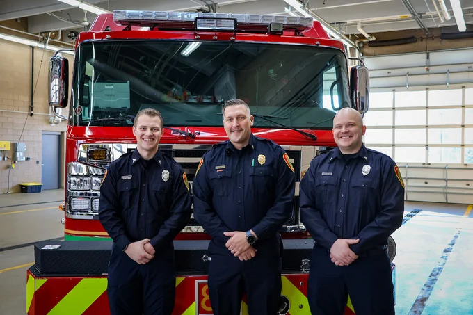 Tommy Gonsior, Chief Andrew Slama and Nate Hilliard standing in front of a Fire Truck at the ceremony. 