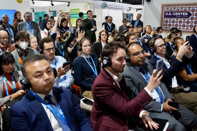Attendees at the "Going All In & All Out" COP29, hosted at the U.S. Center, event taking photos of our esteemed speakers and panelists.