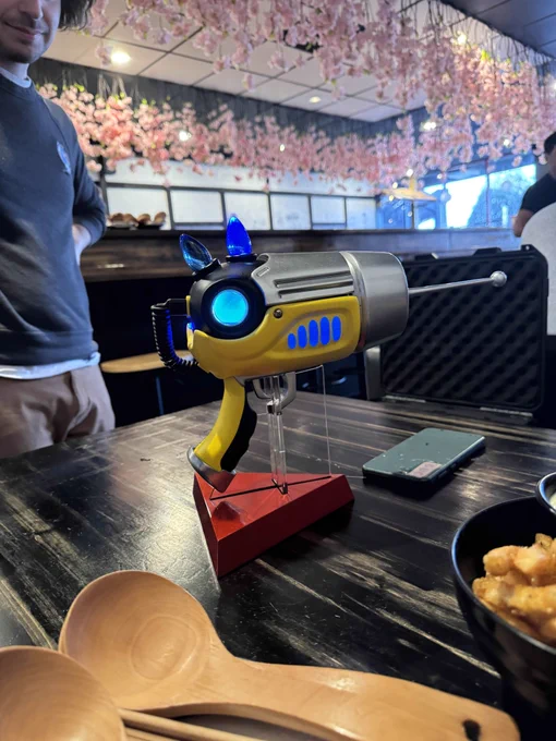 The Ripple Gun, a yellow, chrome, and black sci-fi raygun with an antenna for the barrel and blue lights lit on the top and sides.