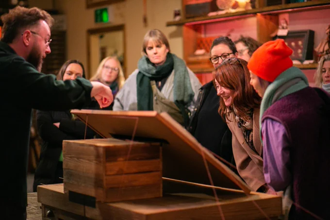 A group of people look eagerly at a corkboard.