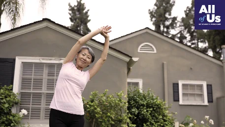 Portrait of a woman stretching outside in front of a house. 