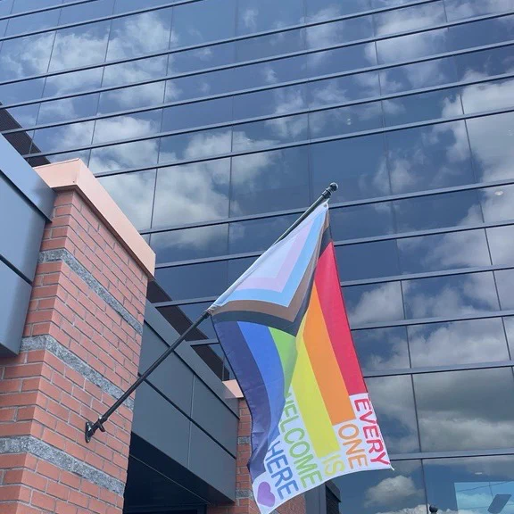 An image of the pride progress flag outside of the SNOLAB surface building in Sudbury, ON. The words, "everyone is welcome here" are written on the flag.