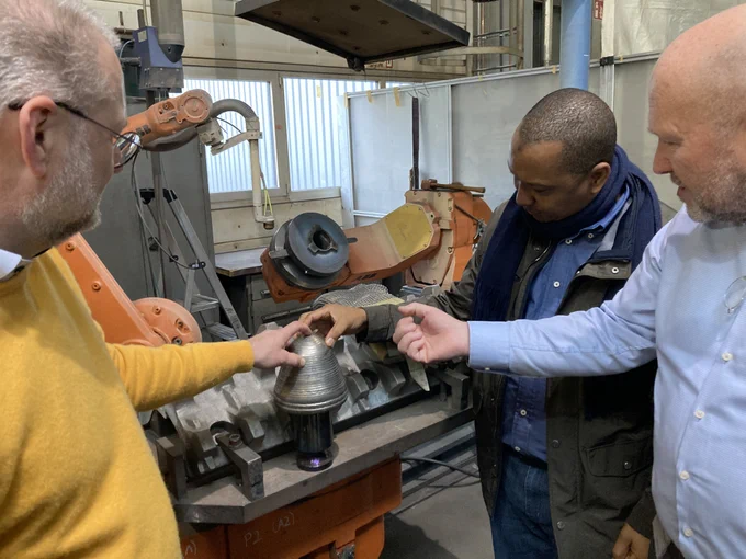 Matthias Gnilke and the Guinean Ambassador, Aliou Barry, and Norbert Neumann (from left to right) looking at the hard facing of a crushing tooth with our TAKRAF WolfRAM Armor, a tungsten carbide overlay.