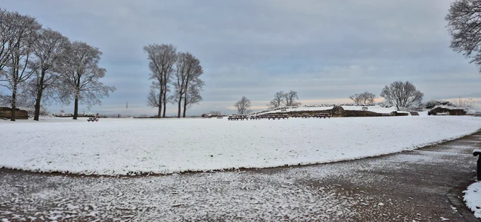 The grassed castle bailey area at Pontefract Castle covered in a dusting of snow, including the picnic benches!
