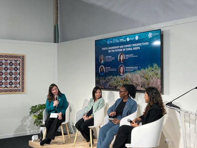 Lauren Gibson (far left) and three other participants sit in a COP29 session titled "YOUTH LEADERSHIP AND EXPERT PERSPECTIVES ON THE FUTURE OF CORAL REEFS."