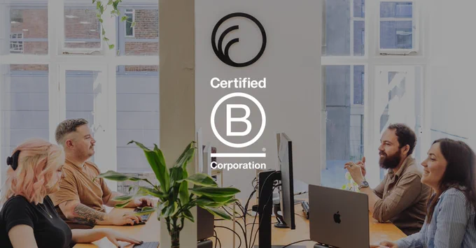 The team at Few and Far having a chat as they work across their desks. Their logo is shown on the wall. In the foreground is the Certified B Corporation logo.
