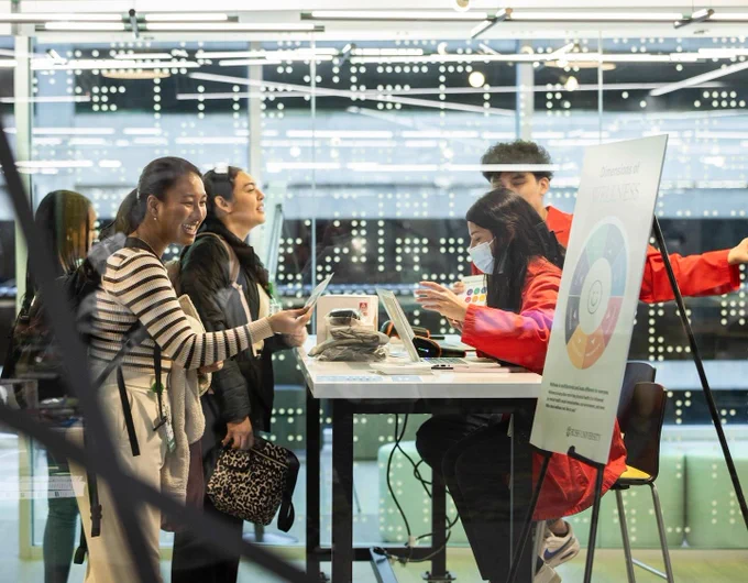 A group of Rush University students interacting at a registration desk, set against a backdrop of a brightly lit, modern space in the Armour Academic Center.