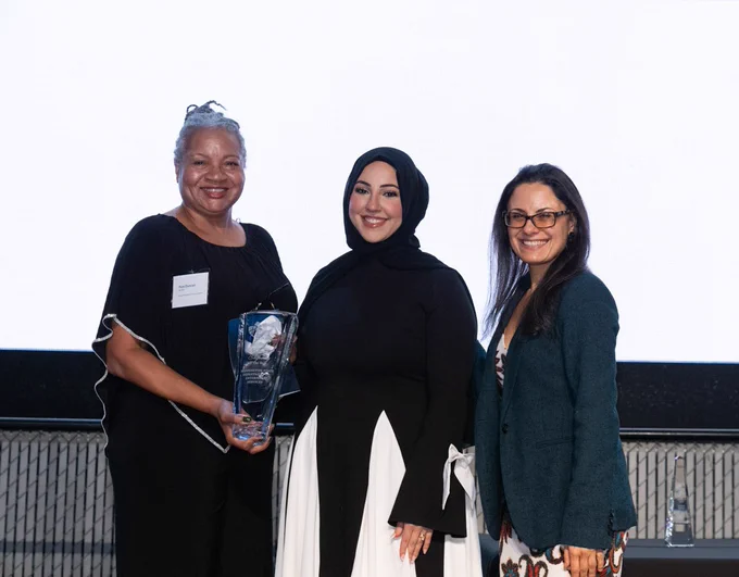 Pam Duncan receiving an award on behalf of DES. She is holding the award next to two other people. 