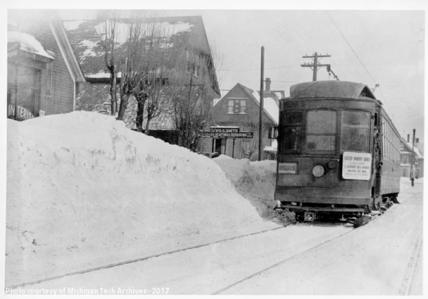 Streetcar moving down a snowy road with high banks