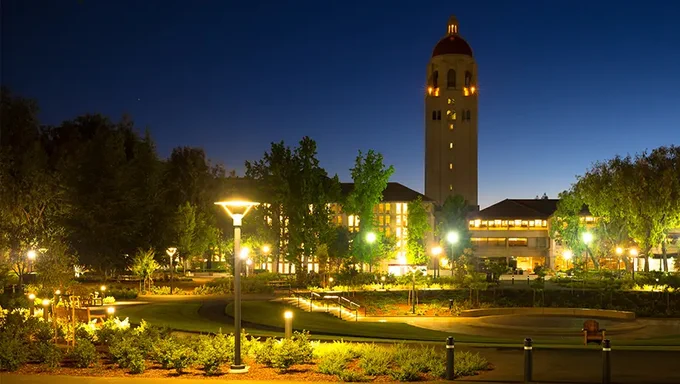 Green Library, East Wing lit up at night, with Hoover Tower in the background.