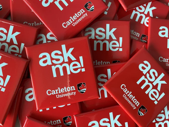 A pile of red buttons with white text reading ask me! The Carleton University logo is centred at the bottom.