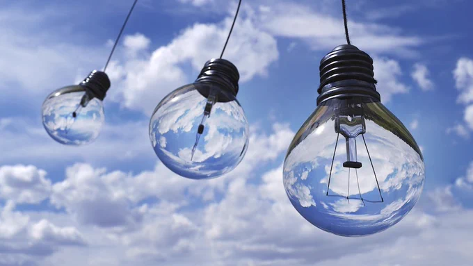 3 clear glass lightbulbs swinging in the fresh air amid white clouds and crisp blue skies--electricity means cleaner air for us all
