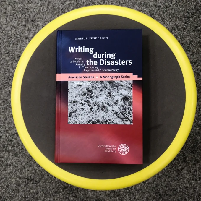 The book "Writing during the Disasters" on a circular grey stand with a yellow outer rim