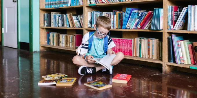 image of a boy reading some books sitting on the floor