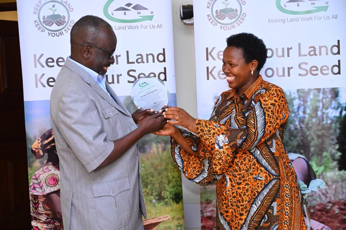 The LEMU incoming Board chairperson, Grace Angeline Chelimo joyfully hands over an accolade to Dr, John Jaramogi Oloya, during a hand over event at LEMU offices in Ntinda 
