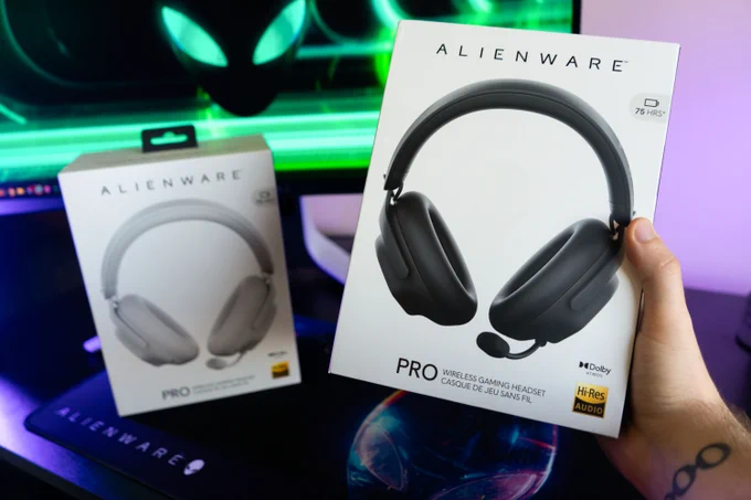 Someone holding a Dark Side of the Moon Alienware Pro Headset with a Lunar Light Alienware Pro Headset in the background.