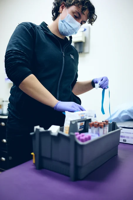 RFU student wearing a mask and gloves and going through a box of clinical supplies