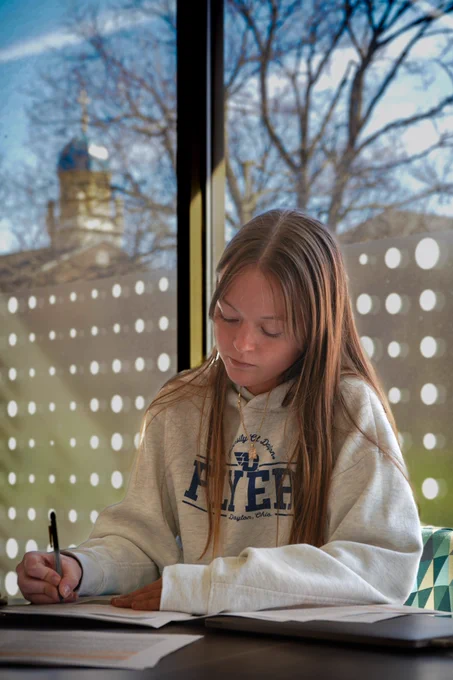 a student studied in front of a window with the chapel in the background