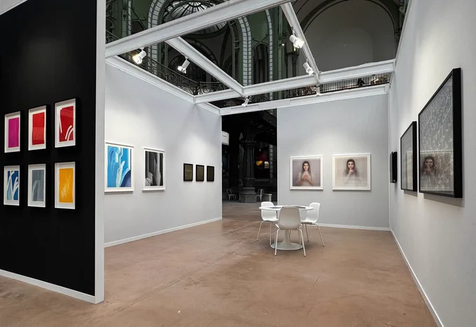 A art fair booth with framed art on the walls
