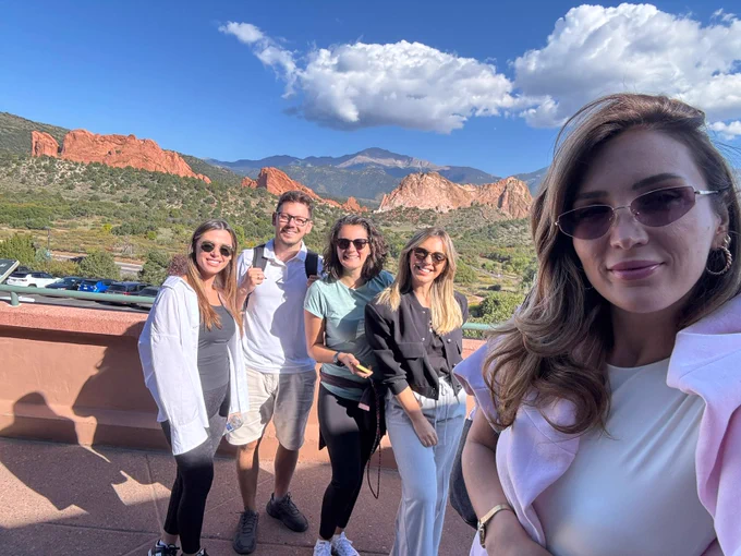 Participants of the International Visitor Leadership Program from Kosovo take a photo in front of a view of mountains in Colorado.